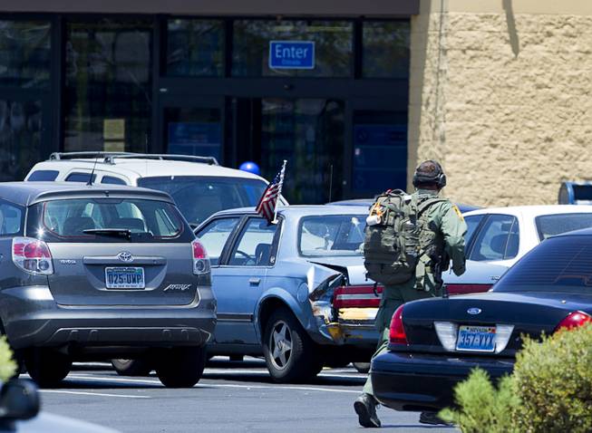 A Metro Police officer runs through the Wal-Mart parking lot on Nellis Boulevard Sunday, June 8, 2014. Two suspects shot two Metro Police officers in a nearby pizza shop then fled to the Wal-Mart where they shot and killed another person, police said. Both officers died of their injuries.