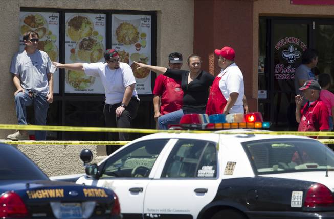 Bystanders watch police activity from a Roberto's Taco Shop behind a Wal-Mart on Nellis Boulevard on Sunday, June 8, 2014. Two suspects allegedly shot two Metro Police officers in a nearby pizza shop, then fled to the Wal-Mart, where they fired shots before killing themselves.