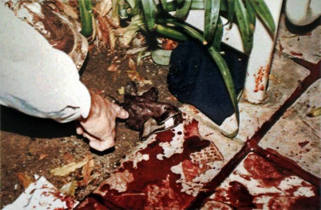 This June 13, 1994, file evidence photo provided by the Los Angeles Police Department shows LAPD's Mark Fuhrman pointing to a pieces of evidence near the body of Nicole Brown Simpson on the bloodstained walkway of her condominium. The photo was introduced as evidence and released for publication, in the 1996 O.J. Simpson wrongful-death civil trial. The O.J. Simpson trial has become a textbook example of what not to do at a crime scene for police and forensic workers.