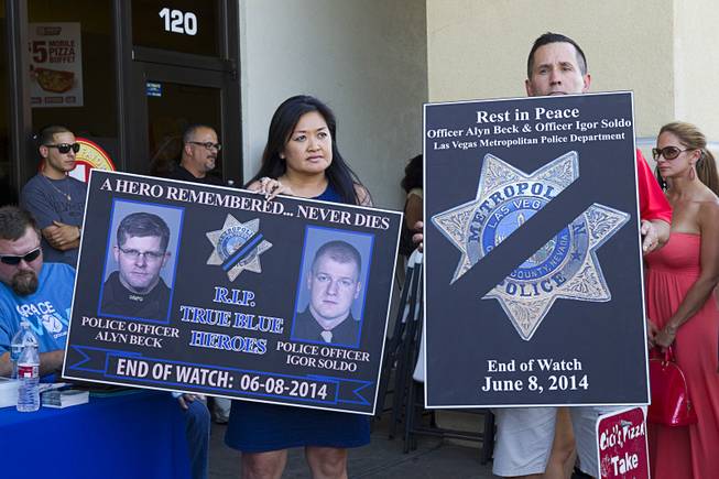Minddie Lloyd, left, and Metro Detective Richard Golgart, representing the Injured Police Officers Fund, hold signs at CiCi's Pizza, where two Metro Police officers were killed, during a community vigil Monday,, Nevada June 9, 2014. Officers Alyn Beck, 41, and Igor Soldo, 31, were ambushed and killed in the restaurant while they were eating lunch on June 8.