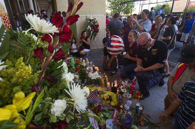 Juvenile probation officers Katie Huncovsky, left, and Patrick Kelso pay their respects at a memorial during a community vigil for slain Metro Police officers in front of CiCi's Pizza Monday,, Nevada June 9, 2014. Officers Alyn Beck, 41, and Igor Soldo, 31, were ambushed and killed in the restaurant while they were eating lunch on June 8.