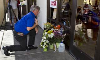 Mike Haskins says a prayer after leaving flowers at a CiCi's Pizza restaurant in honor of two Metro Police officers killed there on Sunday, June 8, 2014. A small memorial was building there and officers were gathered nearby as well in support of their fallen comrades on Monday, June 9, 2014.