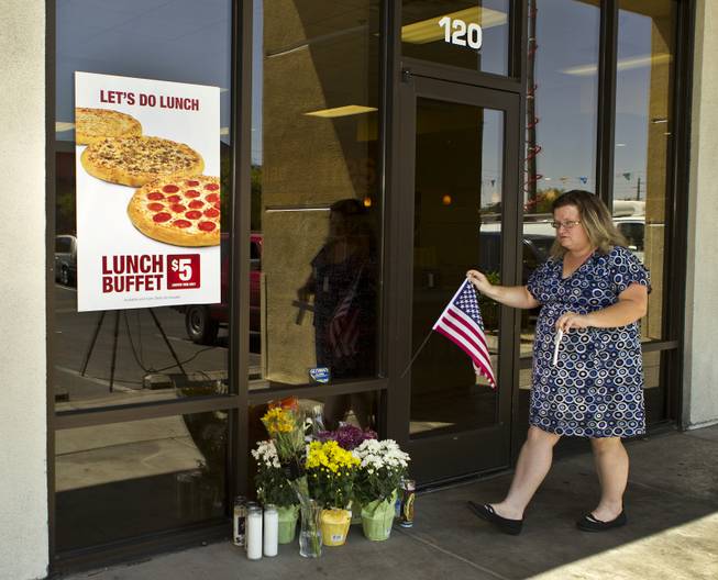 McKenzie Weiss arrives flowers and a cross at a CiCi's Pizza restaurant in honor of two Metro Police officers killed there on Sunday, June 8, 2014. A small memorial was building there and officers were gathered nearby as well in support of their fallen comrades on Monday, June 9, 2014.