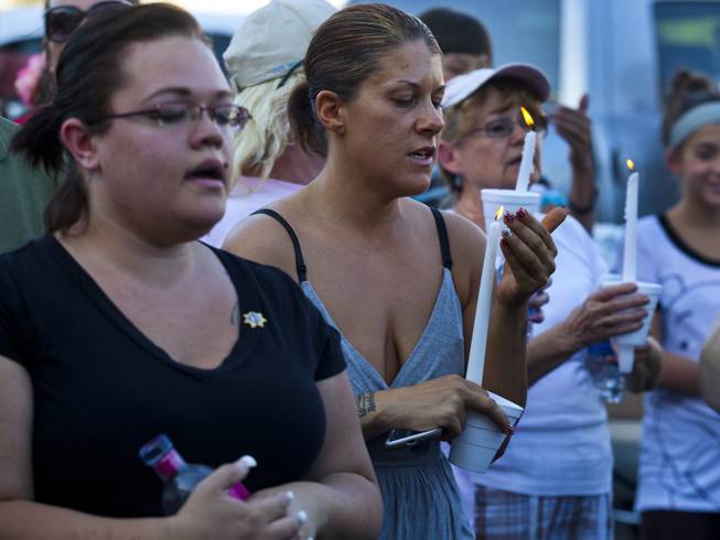 Community members sing with lit candles to honor slain Metro Police officers Alyn Beck and Igor Soldo during a candlelight vigil outside of CiCi's Pizza restaurant on Monday, June 9, 2014.