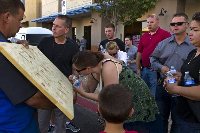 Metro Police officers, family and friends take turns to sign a wooden plaque created by Jason Proctor to honor slain officers Alyn Beck and Igor Soldo on Monday, June 9, 2014.  Many were on hand during a candlelight vigil outside of CiCi's Pizza restaurant to show their support.