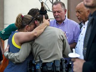 Cheri Rasmussen with the International Church of Las Vegas prays with Metro Police officer T. Bonner following a candlelight vigil outside of CiCi's Pizza restaurant to honor slain officers Alyn Beck and Igor Soldo on Monday, June 9, 2014.  They are joined by Ryan and Mark Rasmussen and other supporters.