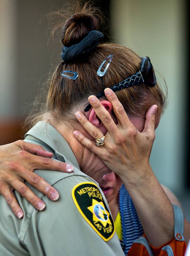 Cheri Rasmussen with the International Church of Las Vegas prays with Metro Police officer T. Bonner following a candlelight vigil outside of CiCi's Pizza restaurant to honor slain officers Alyn Beck and Igor Soldo on Monday, June 9, 2014.  They are joined by Ryan and Mark Rasmussen.
