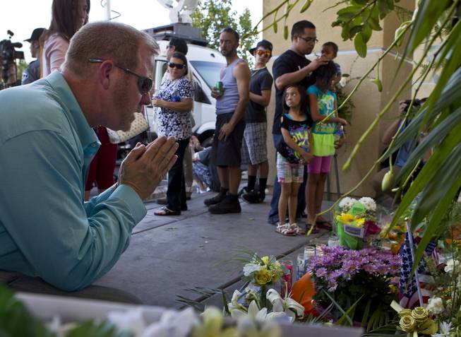 A man prays about a memorial to slain Metro Police officers Alyn Beck and Igor Soldo as community members  gather for a candlelight vigil in their honor outside of CiCi's Pizza restaurant on Monday, June 9, 2014.