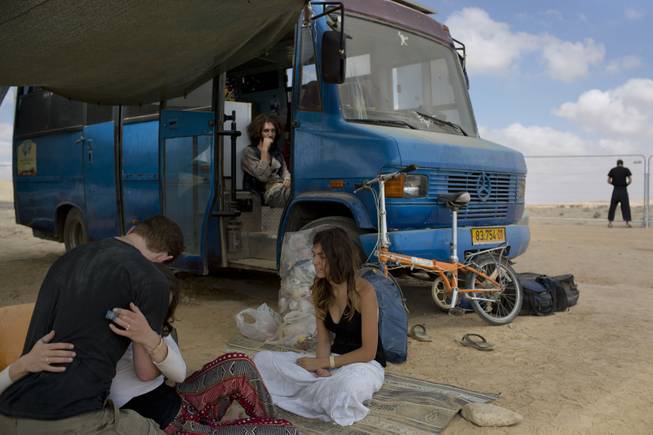 In this photo taken Saturday, June 7, 2014, Israelis sits under the shade during Israelis first Midburn festival in the desert near the Israeli kibbutz of Sde Boker.