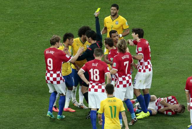Brazil's Neymar, second left, is booked by referee Yuichi Nishimura from Japan after fouling Croatia's Luka Modric, right, during the group A World Cup soccer match between Brazil and Croatia, the opening game of the tournament, in the Itaquerao Stadium in Sao Paulo, Brazil, Thursday, June 12, 2014. 