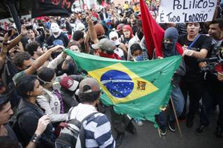 Demonstrators burn a Brazilian flag during a protest against the 2014 World Cup in Belo Horizonte, Brazil, Thursday, June, 12, 2014. The sign in the upper right reads in Portuguese 