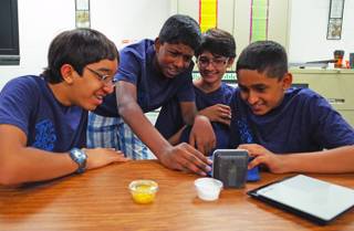 Hyde Park Middle School seventh graders (l-r) Moulin Patel, 13; Ashish Kalakuntla, 12; Anik Patel, 12; and Vidhu Ramakrishnan, 12; look over their invention, which neutralizes pollen, on Tuesday, June 10, 2014. The students will represent Nevada in the national eCybermission competition on June 20.