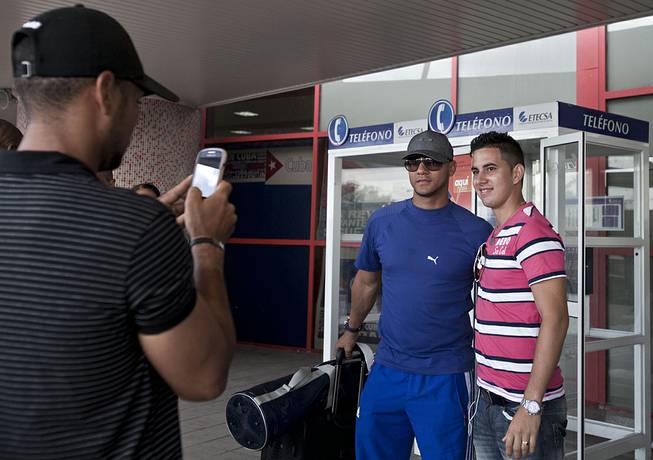 In this May 29, 2014 photo, Yulieski Gourriel, center, a player with Cuba's baseball team Industriales, poses for a photo with a fan before catching his flight at the Jose Marti International Airport, in Havana, Cuba. Gourriel signed a contract with the DeNA BayStars of Yokohama, Japan, for the next half-year. 