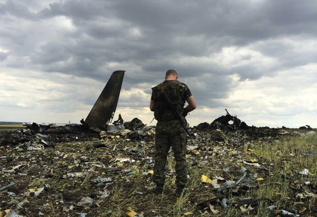 A pro-Russian fighter guards the site of remnants of a downed Ukrainian army aircraft Il-76 at the airport near Luhansk, Ukraine, on Saturday, June 14, 2014. Pro-Russian separatists shot down the military transport plane Saturday in the country’s restive east, killing all 49 service personnel on board, Ukrainian officials said.