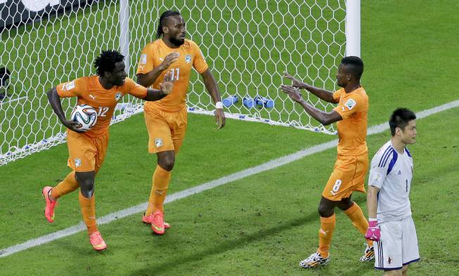 Ivory Coast's Wilfried Bony, left, celebrates with this teammates Didier Drogba, center, and Salomon Kalou, after scoring their first goal against Japan's goalkeeper Eiji Kawashima during the group C World Cup soccer match between Ivory Coast and Japan at the Arena Pernambuco in Recife, Brazil, Saturday, June 14, 2014.