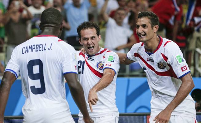 Costa Rica's Marco Urena (21) celebrates with Celso Borges, right, and Joel Campbell (9) after Urena scored his side's third goal during the group D World Cup soccer match between Uruguay and Costa Rica at the Arena Castelao in Fortaleza, Brazil, Saturday, June 14, 2014.