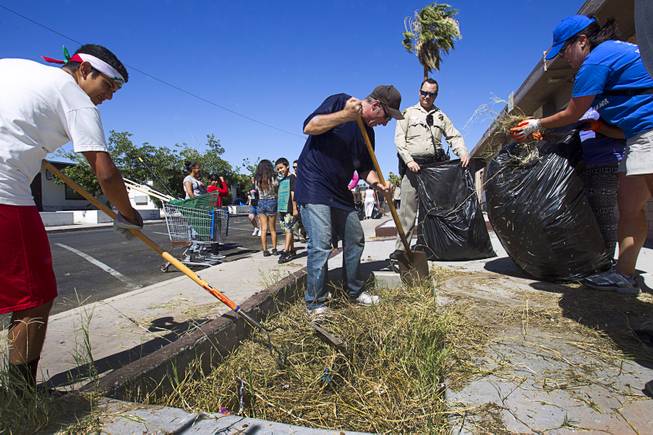 Resident Claudio Solis, 16, left, Carl Thompson, center, and Downtown Dynamo Sarah Ning participate in a Downtown Community Coalition neighborhood cleanup near Fremont Street and 21st Street Tuesday, June 17, 2014. An estimated 8 tons of garbage was collected during the event, said Metro Police Officer Aden Ocampo-Gomez. A bobcat from the city's rapid response unit picked up the larger items such as an abandoned couch and discarded mattresses, he said.