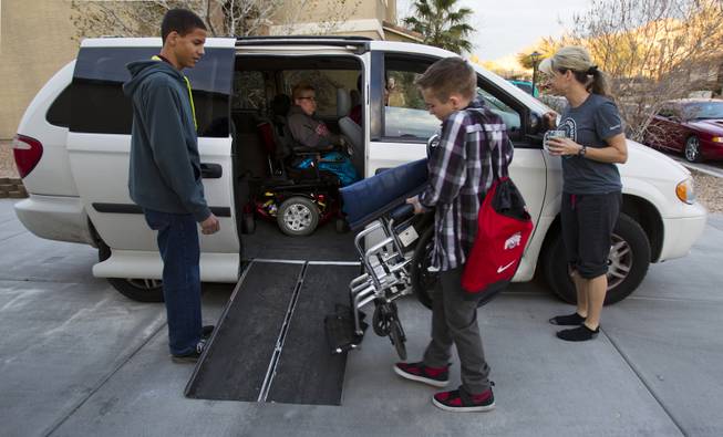 Darius Martin looks on as Hayden Shrum helps to load up his brother Colton with their mother Shelly standing by, preparing to leave for class at Odyssey Charter School on Tuesday, January, 28, 2014.