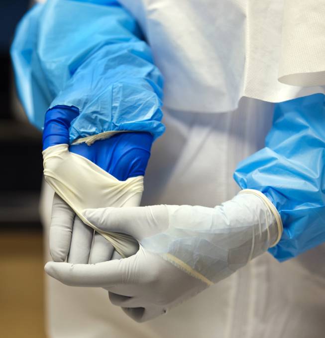 Lab assistant Betsy Sapp shows off her double gloves as part of the safety features of full Personal Protective Equipment (PPE) worn in the BSL-3 laboratory at the Southern Nevada Public Health Laboratory  on Wednesday, June 11, 2014.