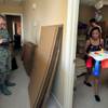 (From right) Rheina Delmundo carries out a small table from her daughter's room as she and family ready for another military move Monday, June 16, 2014.  A1C Jake Carter stands by with Nellis AFB public affairs to ensure things go smoothly.
