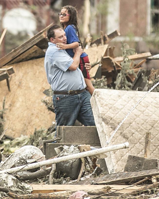 A man holds a girl after she was pulled from the basement of her destroyed home in Pilger, Neb., Monday, June 16, 2014. A hospital spokeswoman says at least one person is dead and at least 16 more are in critical condition after two massive tornadoes swept through northeast Nebraska.