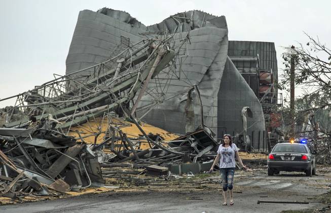 A woman walks down Black Hills Trail road in Pilger, Neb., Monday, June 16, 2014. At least one person is dead and at least 16 more are in critical condition after two massive tornadoes swept through northeast Nebraska on Monday.