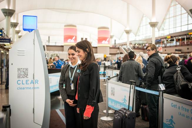 A traveler stops at a Clear kiosk to verify her identity via a fingerprint and make her way through a checkpoint on the way to a security screening.