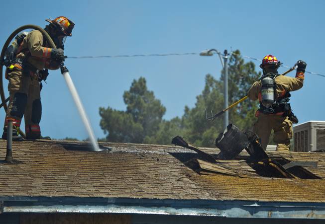 Las Vegas Fire & Rescue hose water through a hole in the roof during an apartment fire at 1820 East Lewis Ave. which spread to a nearby tree and shed on Thursday, June, 19, 2014.