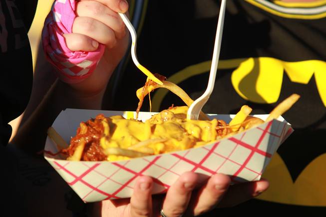 Attendees dig in to a basket of cheesy fries during the Las Vegas stop of the Vans Warped Tour Thursday, June 19, 2014.