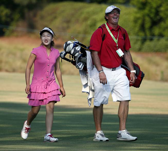 Lucy Li, left, shares a laugh with her caddy as they walk to the second green during a practice round for the U.S. Women's Open golf tournament in Pinehurst, N.C., Wednesday, June 18, 2014. The sixth-grader from California is the youngest qualifier in the history of the U.S. Women's Open.