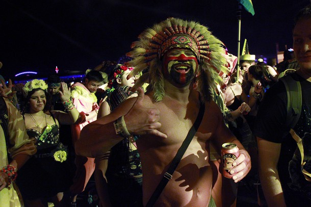 An attendee wearing a native American headdress listens to a set during the first night of the Electric Daisy Carnival Saturday, June 21, 2014 at the Las Vegas Motor Speedway.