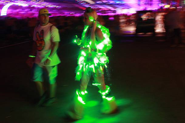 A woman festooned in lights walks with a young man during the first night of the Electric Daisy Carnival early Saturday, June 21, 2014 at the Las Vegas Motor Speedway.