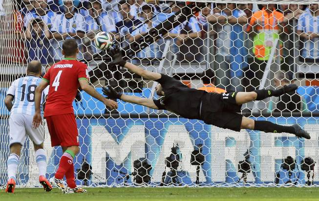 Argentina's Rodrigo Palacio and Iran's Jalal Hosseini watch as Iran's goalkeeper Alireza Haghighi dives but allows a goal by Argentina's Lionel Messi during a World Cup soccer match at the Mineirao Stadium in Belo Horizonte, Brazil, on Saturday, June 21, 2014. Argentina defeated Iran 1-0.