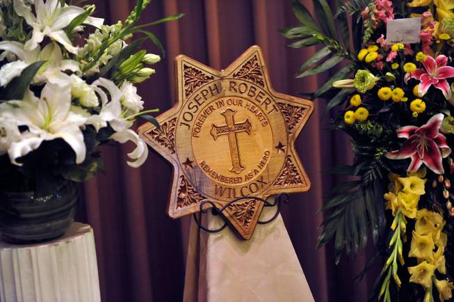 A wood-engraved placard for Joseph Wilcox is displayed during a memorial service at Palm Downtown Mortuary and Cemetery on Sunday, June 22, 2014. Wilcox, 31, was killed trying to stop Jerad and Amanda Miller in the midst of their shooting spree at an east valley Wal-Mart store June 8.