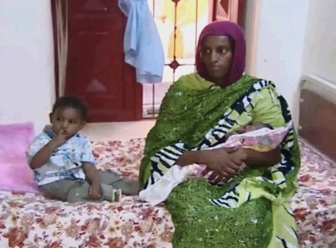 In this file image made from an undated video provided Thursday, June 5, 2014, by Al Fajer, a Sudanese nongovernmental organization, Meriam Ibrahim, sitting next to Martin, her 18-month-old son, holds her newborn baby girl that she gave birth to in jail last week, as the NGO visits her in a room at a prison in Khartoum, Sudan. Sudan's official news agency, SUNA, said the Court of Cassation in Khartoum on Monday, June 23, canceled the death sentence against 27-year-old Meriam Ibrahim after defense lawyers presented their case. The court ordered her release.