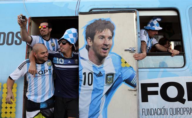 Argentine fans arrive in a bus decorated with a painting of soccer star Leonel Mesi at the Copacabana beach in Rio de Janeiro, Brazil,  Saturday June 14, 2014. Waving flags and banners, more than a thousand Argentine fans, many dressed in their team's traditional blue and white, crowded the Copacabana beachfront ahead of Argentina's World Cup match against Bosnia-Herzegovina Sunday in Rio's iconic Maracana stadium.