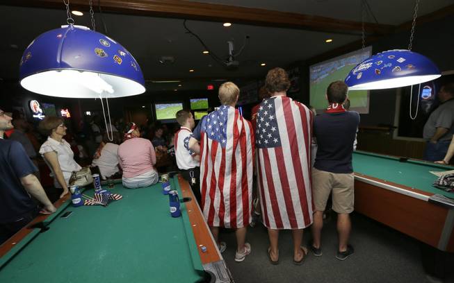 Fans draped in flags watch the World Cup Soccer match between the United States and Germany at a local bar, Thursday, June 26, 2014, in West Des Moines, Iowa. 
