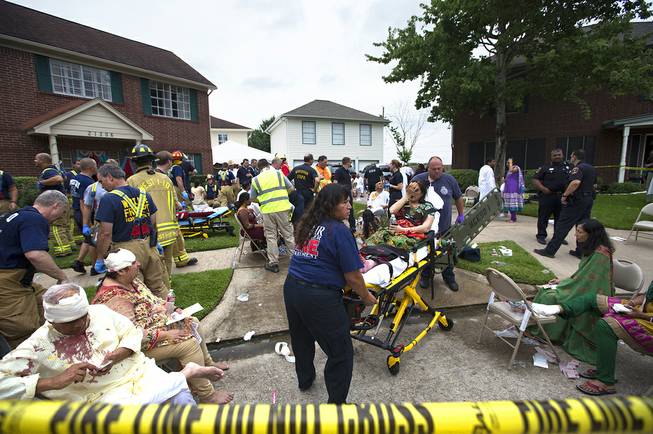 Firefighters and emergency crews treated people outside in a makeshift triage area set up in the front yards of nearby homes after a floor collapsed under a large crowd of people gathered for a religious event Thursday, June 26, 2014, in Katy, Texas.