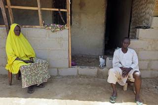 In this Monday, June 2, 2014 photo, Rabi Abdullahi, left, sits with her husband, Haruna Abdullahi, outside their home in Kaduna, Nigeria. They are the parents of Maimuna Abdullahi. Maimuna wore the scars of an abused woman anywhere: A swollen face, a starved body, and, barely a year after her wedding, a divorce. But for Maimuna, it all happened by the time she was 13. Maimuna is one of thousands of divorced girls in Nigeria who were married as children and then got thrown out by their husbands or simply fled. (AP Photo/Sunday Alamba)