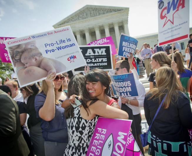 Demonstrators embrace as they react to hearing the Supreme Court's decision on the Hobby Lobby case outside the Supreme Court in Washington, Monday, June 30, 2014. The Supreme Court says corporations can hold religious objections that allow them to opt out of the new health law requirement that they cover contraceptives for women.