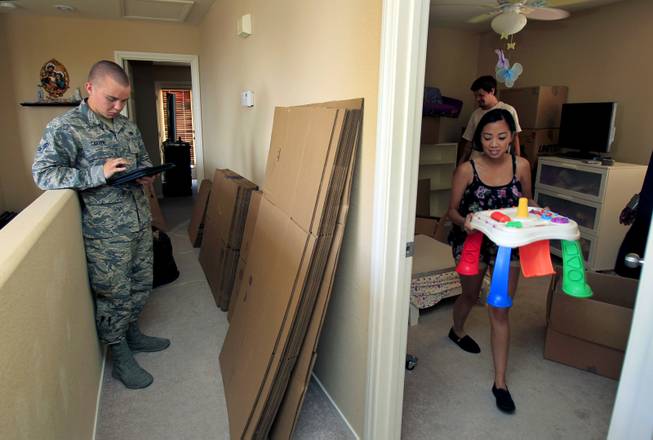 (From right) Rheina Delmundo carries out a small table from her daughter's room as she and family ready for another military move Monday, June 16, 2014.  A1C Jake Carter stands by with Nellis AFB public affairs to ensure things go smoothly.  L.E. Baskow