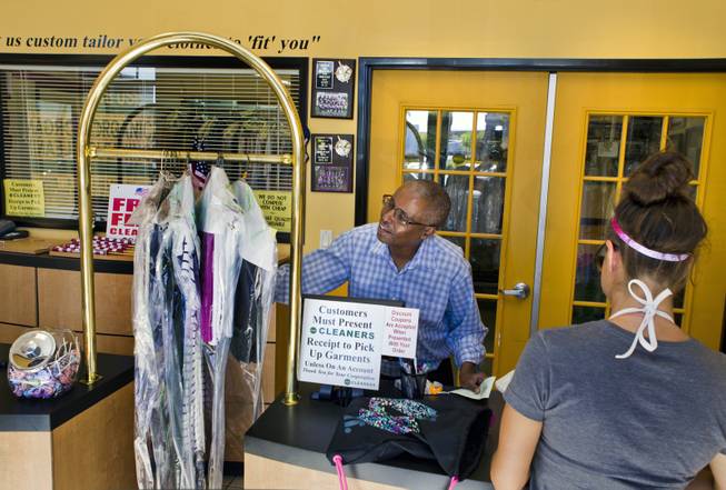 Mahamed Youssouf, owner of the Green Cleaners Alteration Center, calculates a customer's order on Wednesday, July 3, 2014. He is giving away 500 flags and cleaning flags for free in honor of the Fourth of July.