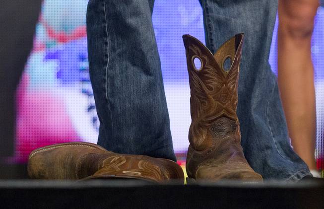 Welterweight Kenny Robertson kicks off his cowboy boots during the UFC 175 weigh ins at the Mandalay Bay Resort on Friday, July 4, 2014.