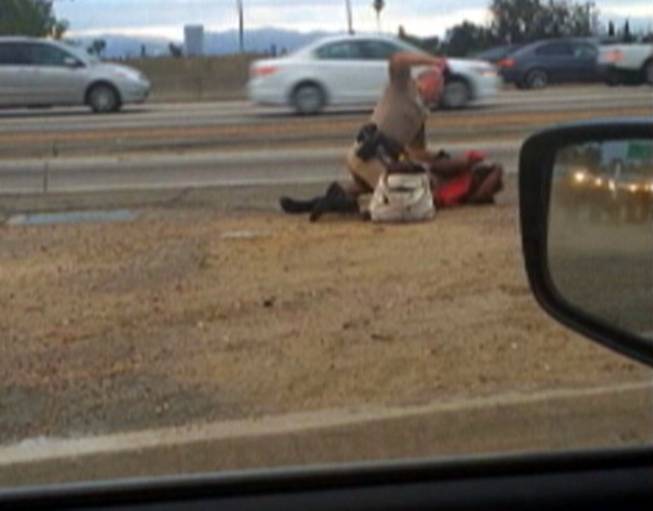 In this July 1, 2014, file image made from video provided by motorist David Diaz, a California Highway Patrol officer punches Marlene Pinnock, 51, on the shoulder of a Los Angeles freeway.