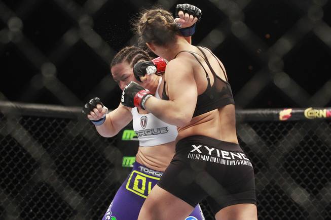 Ronda Rousey hits Alexis Davis with a right during their fight at UFC 175 at the Mandalay Bay Events Center Saturday, July 5, 2014. Rousey retained her title with a 16-second TKO.