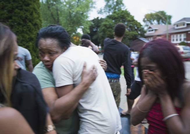 In this Saturday, July 5, 2014, photo, Georgia Utendahl, left, and Shanice Smith, right, grieve after learning that their family member was shot by police on Chicago's South Side. The Fourth of July weekend was a bloody one in Chicago, where at least nine people were shot to death and at least 60 others were wounded.