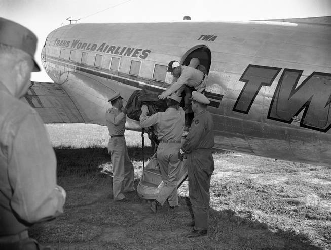 First of eight more bags containing portions of unidentified people who died in the crash of a TWA Constellation near here on Saturday, June 30, is loaded aboard a plane for flight to the coroner's office in Flagstaff in Grand Canyon, Arizona , July 3, 1956. Seven more bags are expected to be flown out from the crash where 70 died. This will complete the TWA search and four bags from the UAL crash are expected to be flown out. 