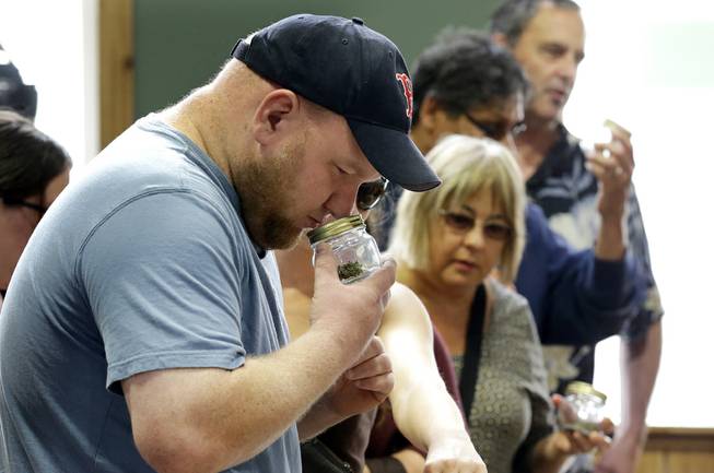 A customer, who declined to give his name, sniffs a strain of recreational marijuana at Top Shelf Cannabis, Tuesday, July 8, 2014, in Bellingham, Wash., during the first half-hour of legal sales in the states. 