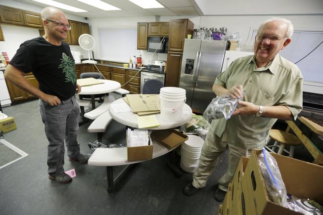 Bob Leeds, owner of Sea of Green Farms, right, has a laugh with farm director Phil Tobias, as they load packets of recreational marijuana into boxes, Tuesday, July 8, 2014, in Seattle, for delivery to a store in Bellingham, Wash. It was the first delivery for the company since retail licenses were issued by the state on Monday.