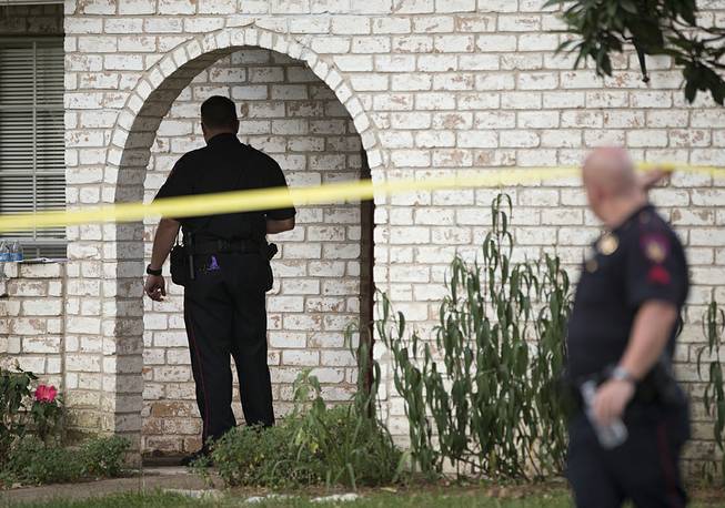 Law enforcement officers investigate the scene of a shooting Wednesday, July 9, 2014, in Spring, Texas. A Harris County Sheriff's Office statement says precinct deputy constables were called to a house about 6 p.m. Wednesday and found two adults and three children dead. Another child later died at a hospital. 